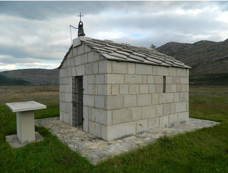 Two women in business attire review documents together in an office, standing near a wall with papers and sticky notes.